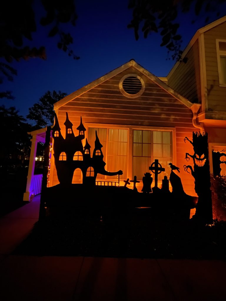 Night view of the DIY Silhouette Decor for halloween - The haunted house and graveyard with spooky tree silhouette back lit with orange flickering lights.