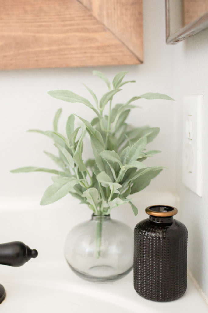 Bathroom makeover - Grey vase and black bottle with Faux greenery from Hobby lobby on vanity for decor.