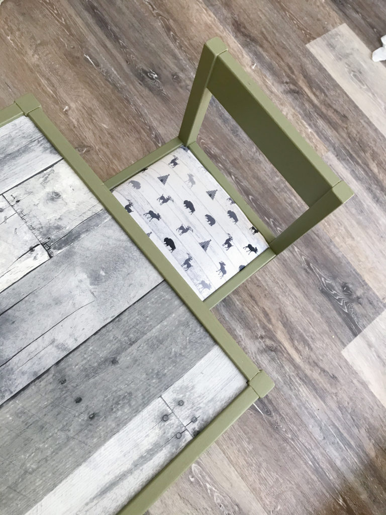 Ikea table and chair for boys room with 'Olive Grove' by BM paint, white 'woodland animal' fabric cushions, and 'wood' wallpaper tabletop. 